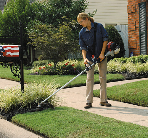 Women trimming weeds in her front yard with a Honda Trimmer